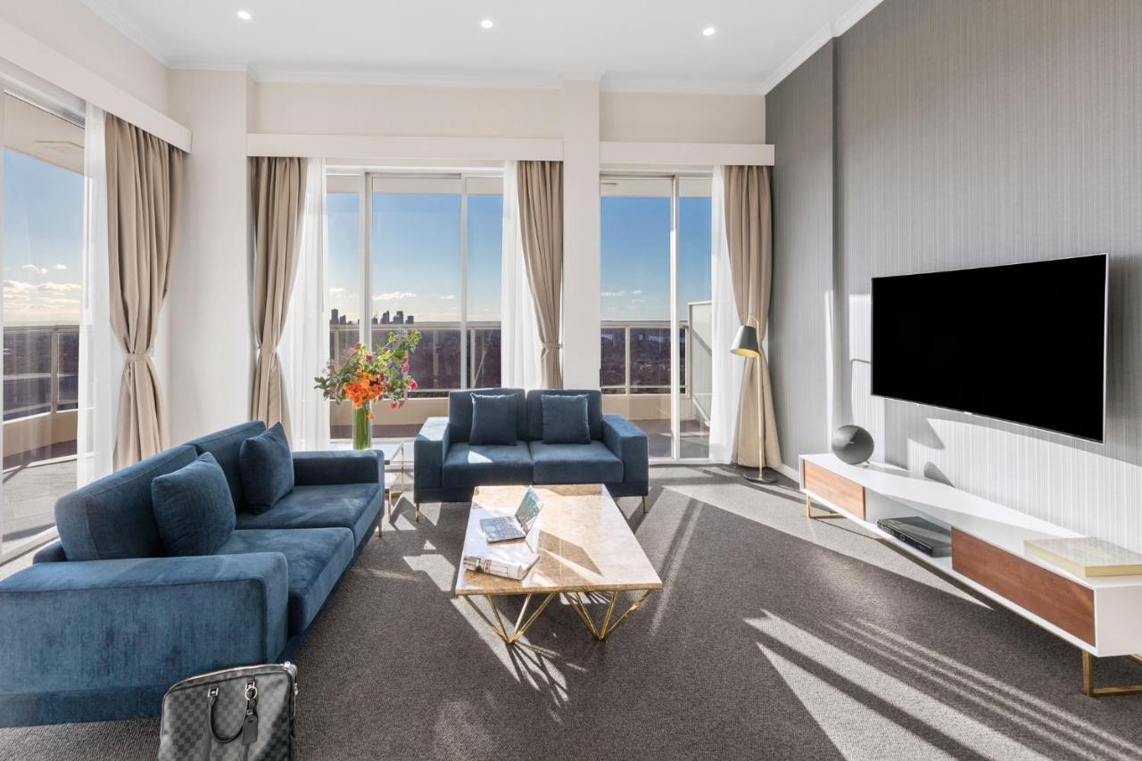Meriton Suites Bondi Junction Σίδνεϊ Εξωτερικό φωτογραφία The photo depicts a modern living room with a stylish and contemporary design. It features a cozy seating arrangement with a blue sofa and two matching armchairs. In front of the seating area is a coffee table with a geometric design. The room has la