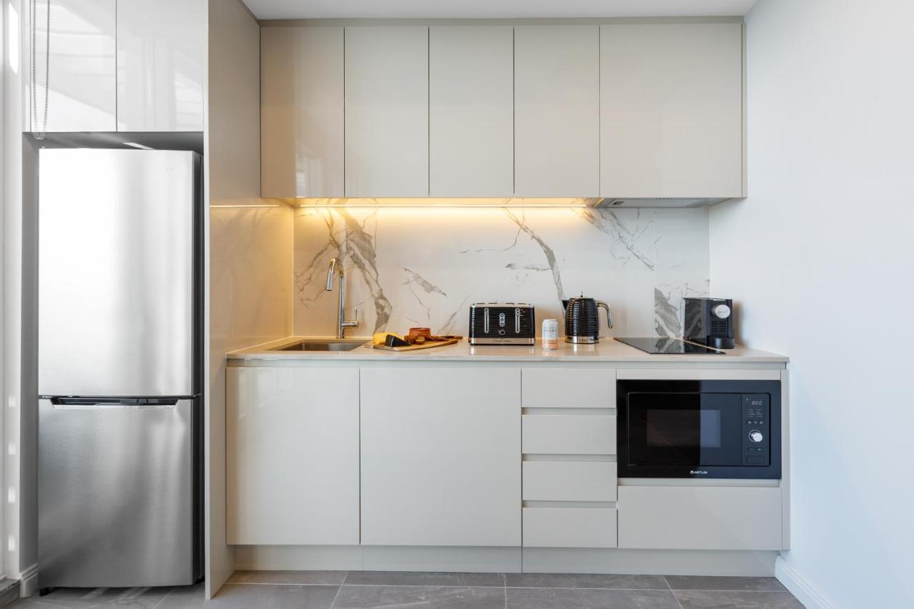 Meriton Suites Bondi Junction Σίδνεϊ Εξωτερικό φωτογραφία The photo shows a modern kitchen featuring a sleek design. It includes light-colored cabinetry with a smooth finish and upper cabinets that blend seamlessly with the wall. The countertop is made of a light stone, complementing the overall aesthetic. 
